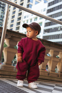 Toddler wearing a burgundy romper with a relaxed fit, perfect for cool weather comfort.

