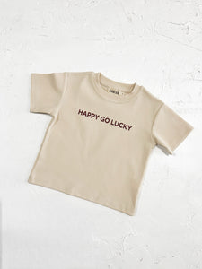 Close-up of a t-shirt featuring "Happy Go Lucky" text, laid out