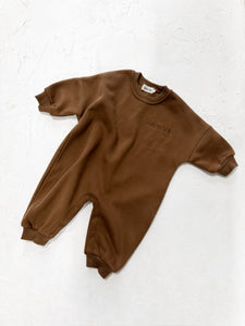 A chocolate brown all-in-one romper with snap closures and soft ribbed fabric.