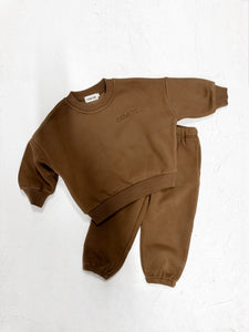 Flat lay of a chocolate kids lounge set featuring a long sleeve top and pants.

