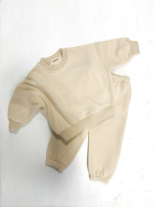 Flat lay of a cream kids lounge set featuring a long sleeve top and pants.